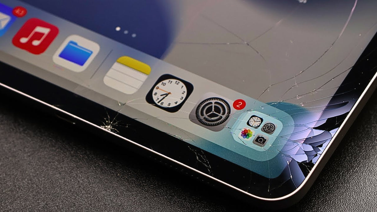 Ipad with cracked screen and app icons on a dark surface
