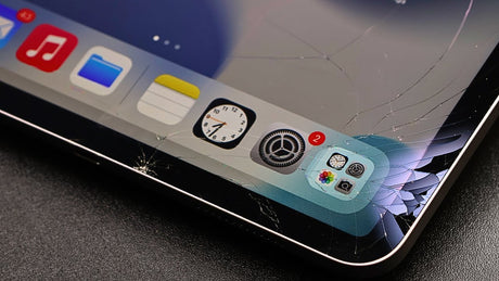 Ipad with cracked screen and app icons on a dark surface